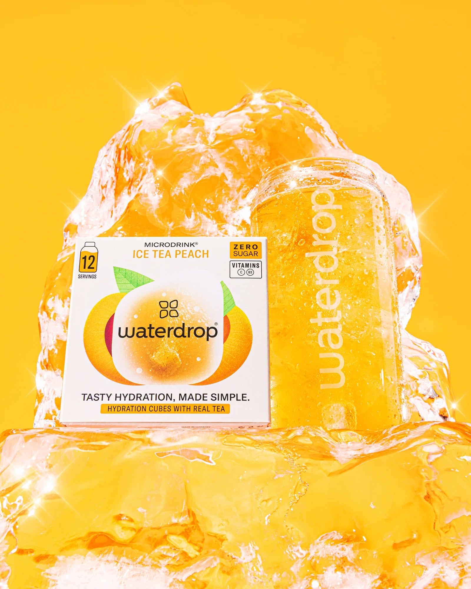 Cutie Microdrink Ice Tea Peach cu 12 porții, lângă o sticlă waterdrop umplută cu ceai rece de piersică, înconjurată de gheață, pe fundal galben.