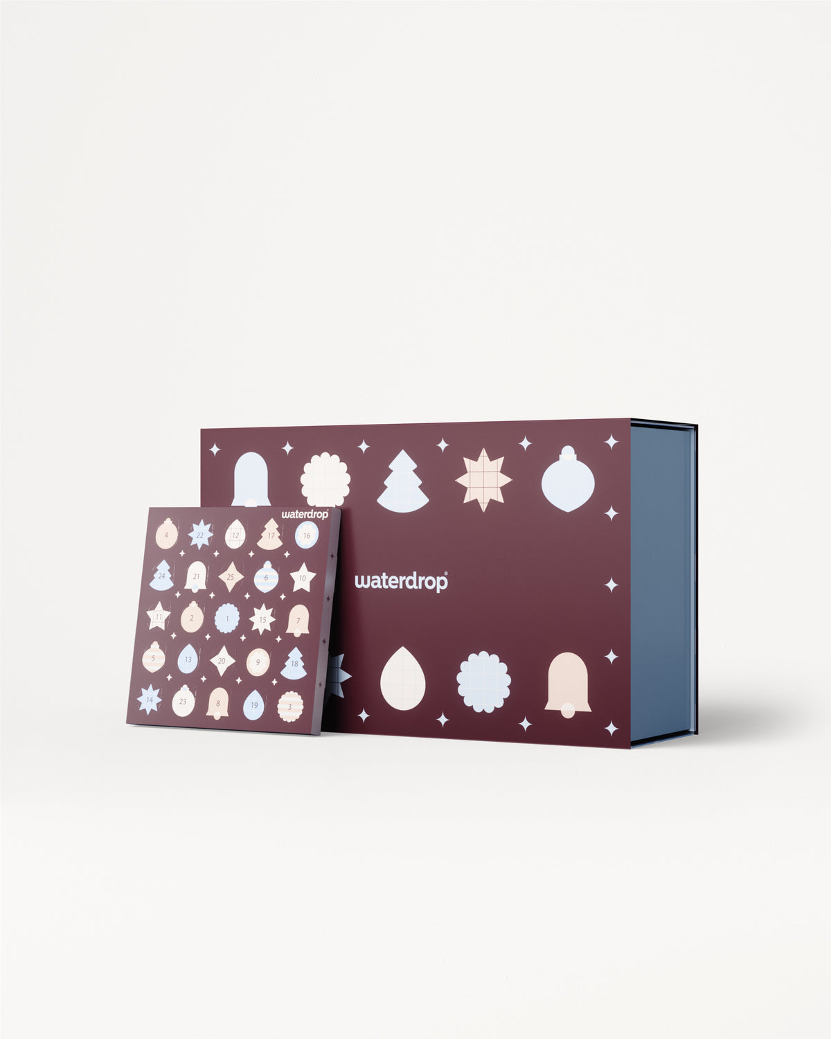Calendar de Advent cu panouri violete și ornamente albe, prezentat alături de o cutie interioară albastră.