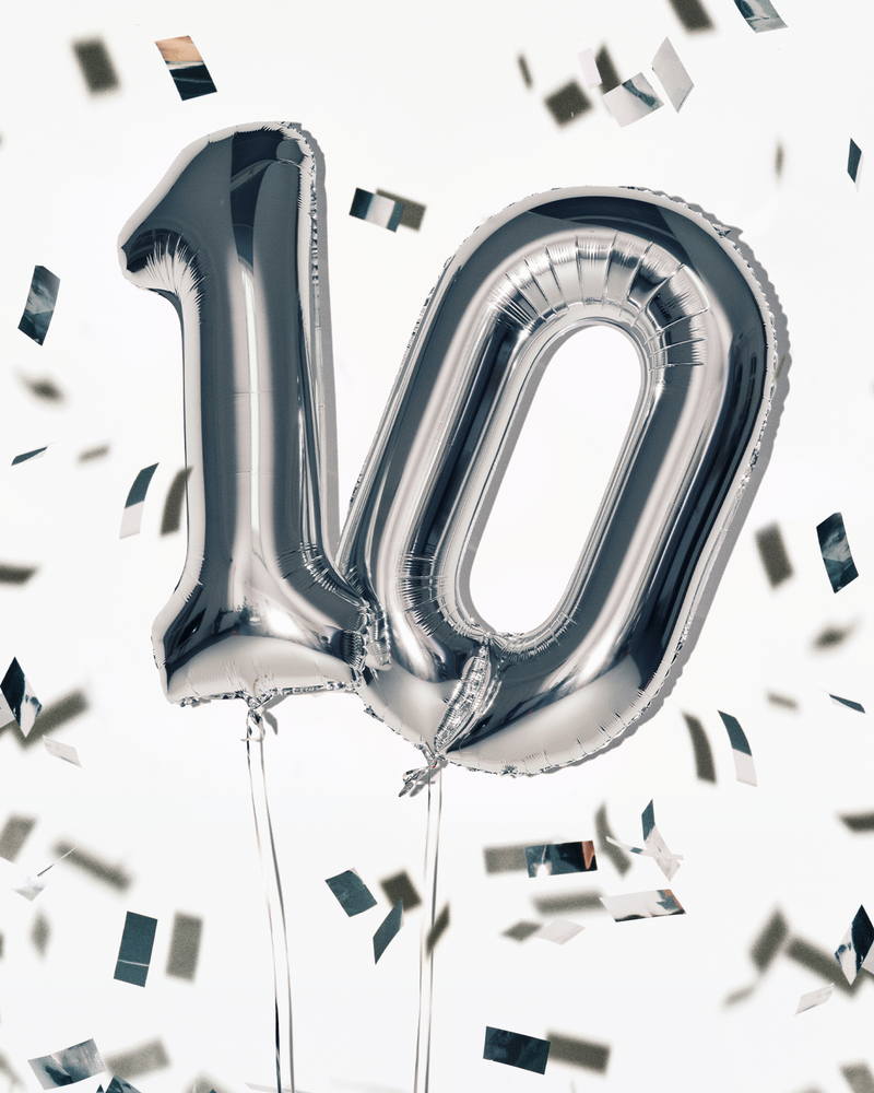 Baloni de folie argintii în formă de cifra 100, cu sfori, înconjurați de confetti.